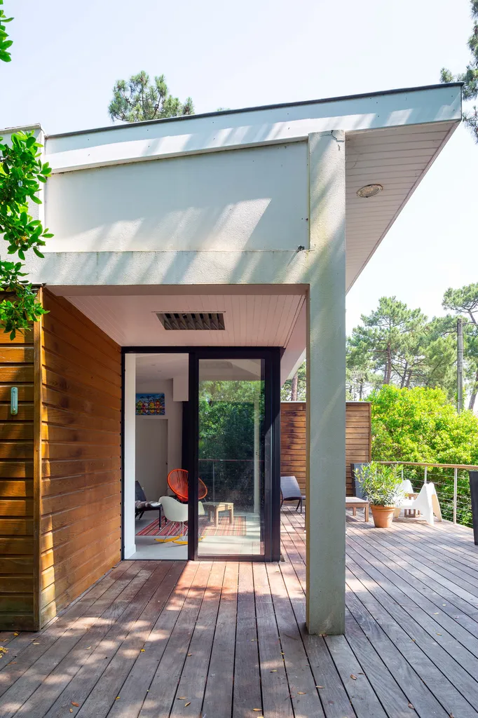 Vue intérieure – salon ouvert sur la pinède  AKIKO ARCHITECTURE — Piraillan, Cap-Ferret — extension bois & réaménagement Le salon repensé s’ouvre largement sur la terrasse grâce à une baie toute hauteur imaginée pour prolonger le séjour vers la pinède. L’