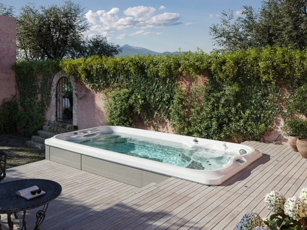 Spa Jacuzzi J16 PowerPro dans un jardin avec un aménagement en terrasse bois tout autour
