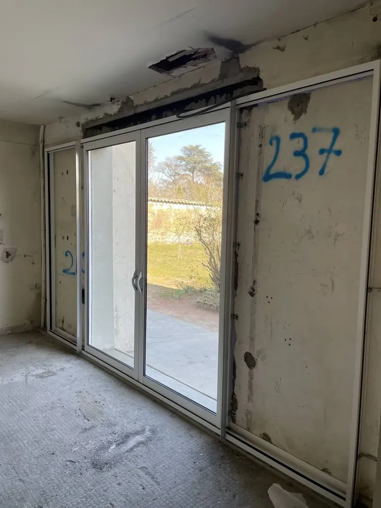 Pose d’une baie vitrée coulissante en aluminium après ouverture du mur porteur, avec mise en place de l’étanchéité