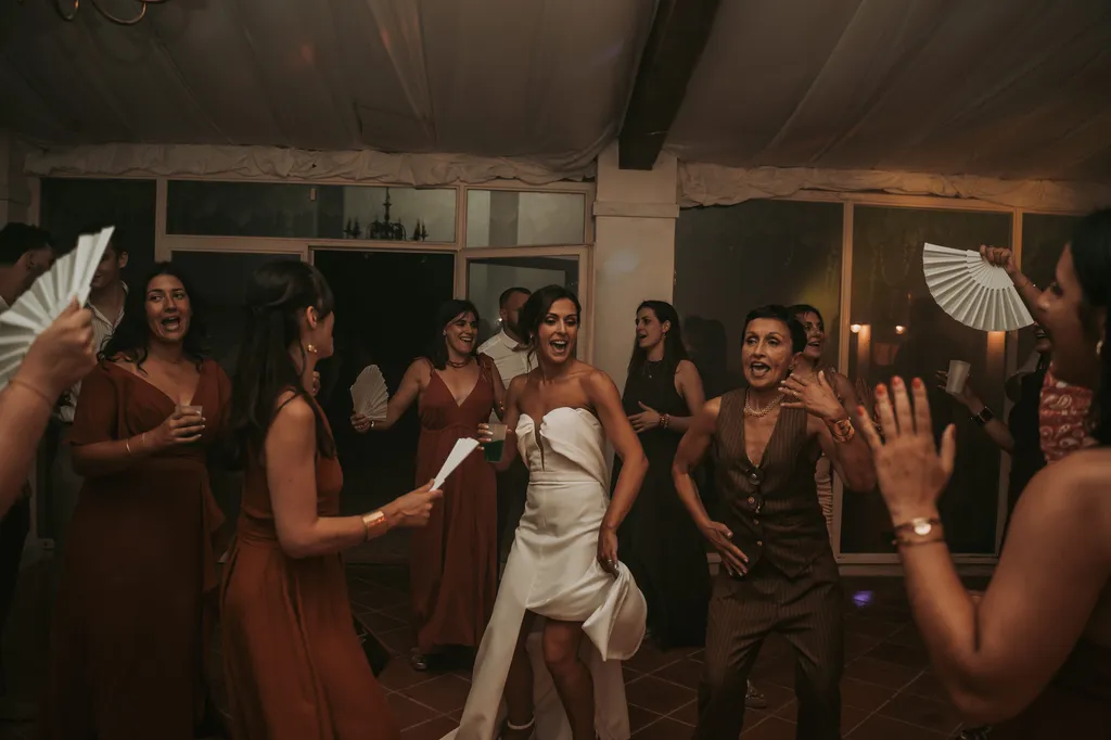 La mariée sur la piste de danse, entourée de ses proches, dans l'élan d'une soirée de mariage.