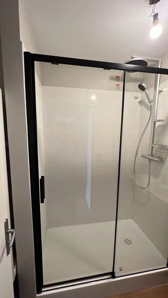 Plombier pour rénovation salle de douche Le Havre : remplacement meuble vasque et douche moderne avec porte coulissante