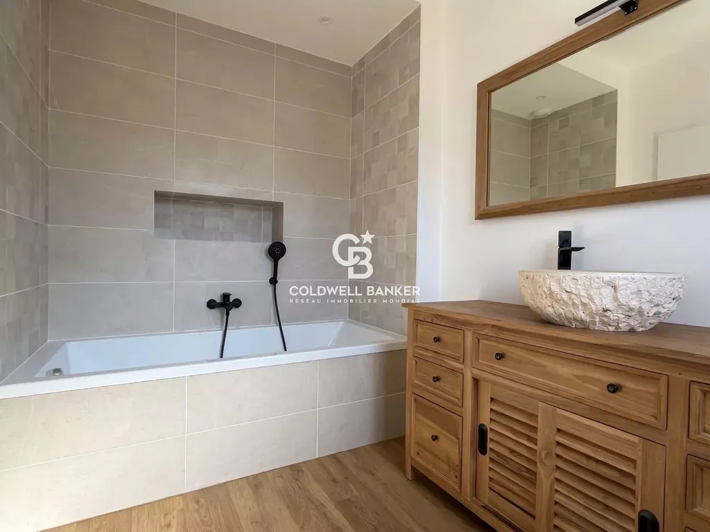 Salle de bains avec baignoire, meuble en bois et vasque en pierre, maison entièrement rénovée en Sarthe