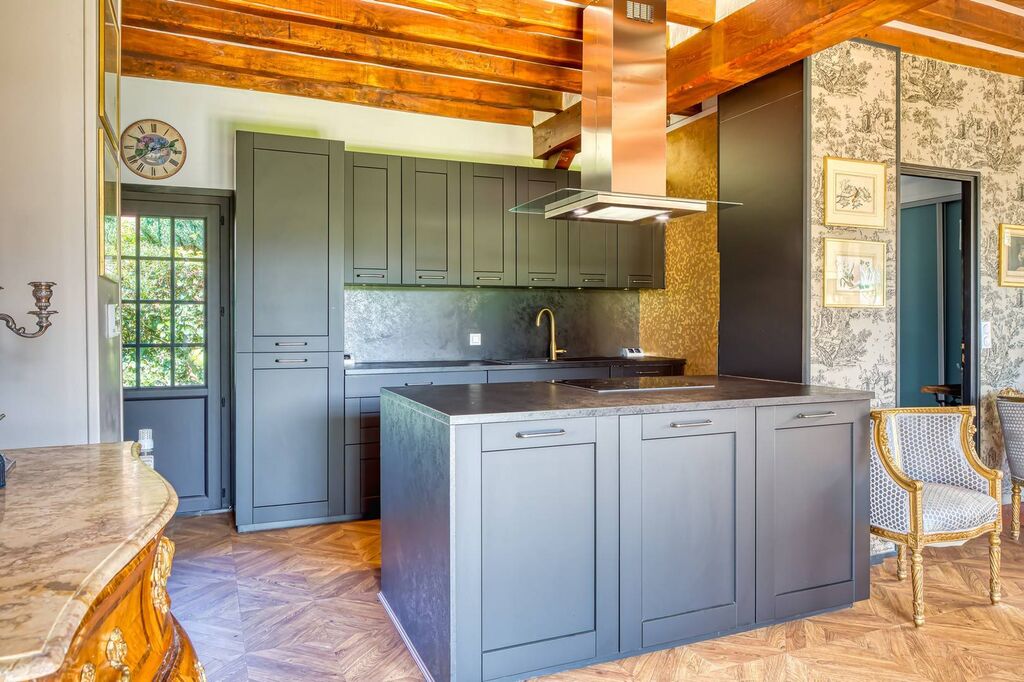 Achat maison en Normandie avec jardin paysagé : Cuisine aménagée, séjour avec cheminée, véranda lumineuse de 40 m² et deux suites parentales avec salles d’eau.