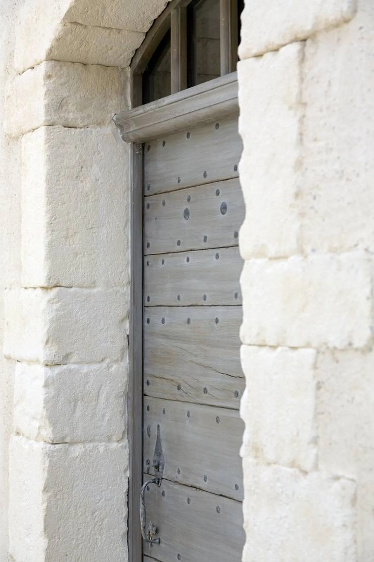 Porte en bois de récupération avec encadrement en pierre de taille de Beaulieu posée de façon harpée