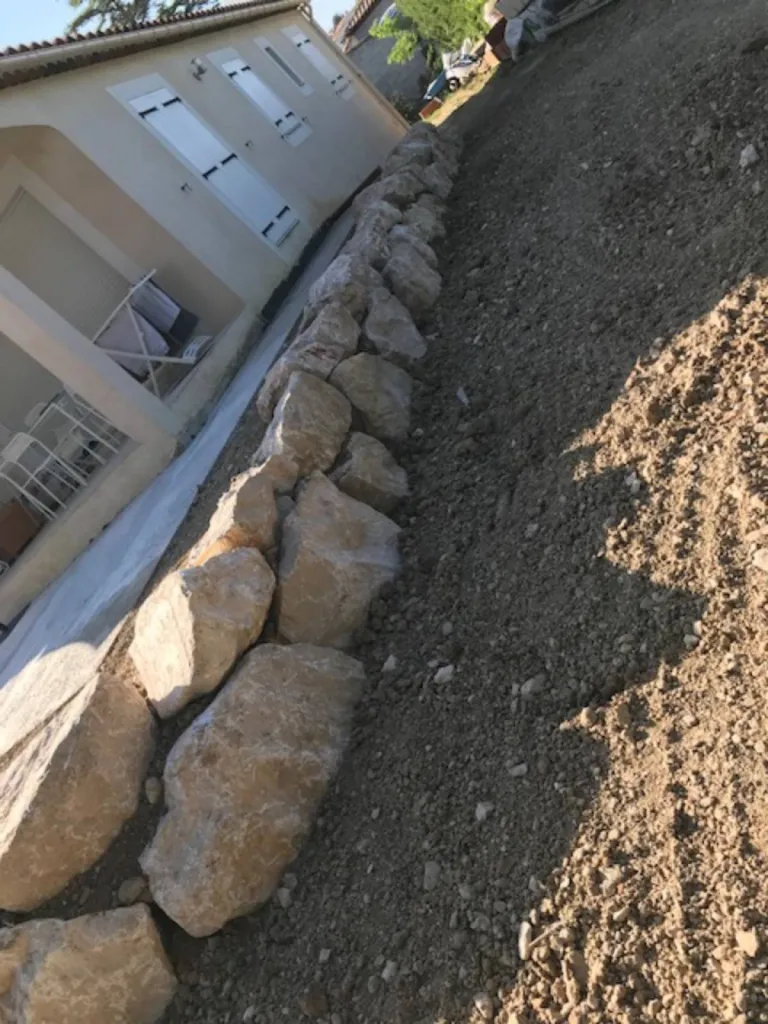 Enrochement d’un terrain en pente autour d’une terrasse en bois composite à Eiguilles