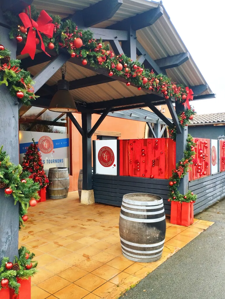 Décoration de Noël de la Cave des Tournons avec sapins synthétiques, guirlandes artificielles et tableaux de Noël garnis de boules rouges gourmandes à Charnay-lès-Mâcon
