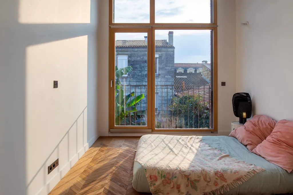 Chambre en étage créée lors de la surélévation imaginée par AKIKO ARCHITECTURE, offrant une vue panoramique sur les toits de Bordeaux Nansouty