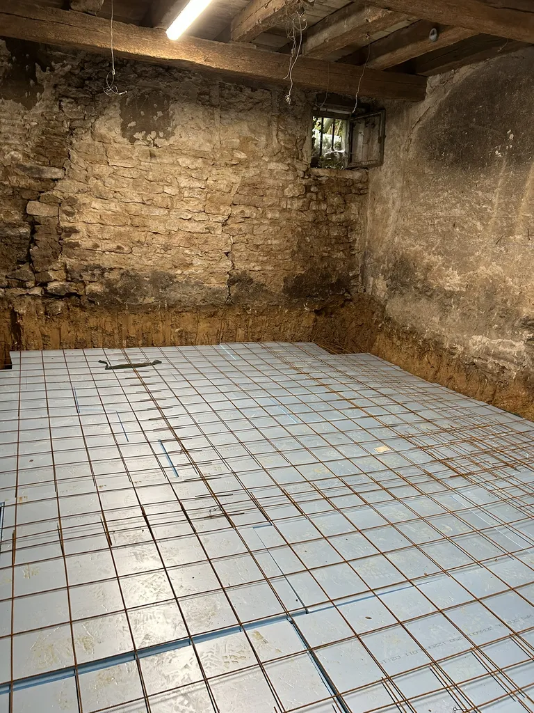 Mise en place de l’isolant et du treillis soudé avant le coulage de la dalle béton lors de travaux de maçonnerie dans une maison à Anse (Rhône – 69)
