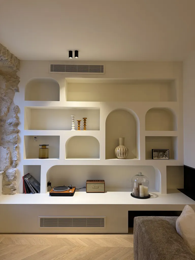 Meuble de cheminée sur mesure avec niches arrondies et banquette intégrée réalisé pour une maison dans le Sud Ardèche