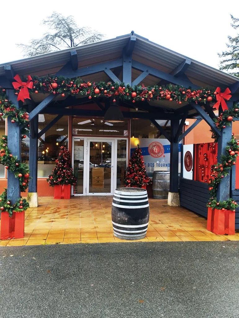 Décoration de Noël de la Cave des Tournons avec sapins synthétiques, guirlandes artificielles et tableaux de Noël garnis de boules rouges gourmandes à Charnay-lès-Mâcon