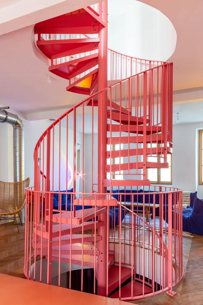 Escalier hélicoïdal rouge dessiné par AKIKO ARCHITECTURE, élément central du projet à Nansouty reliant les niveaux dans une verticalité créative
