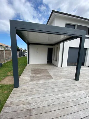Pergola bioclimatique de couleur grise avec lames orientables de couleur blanche adossée à la façade sur la commune du Teich
