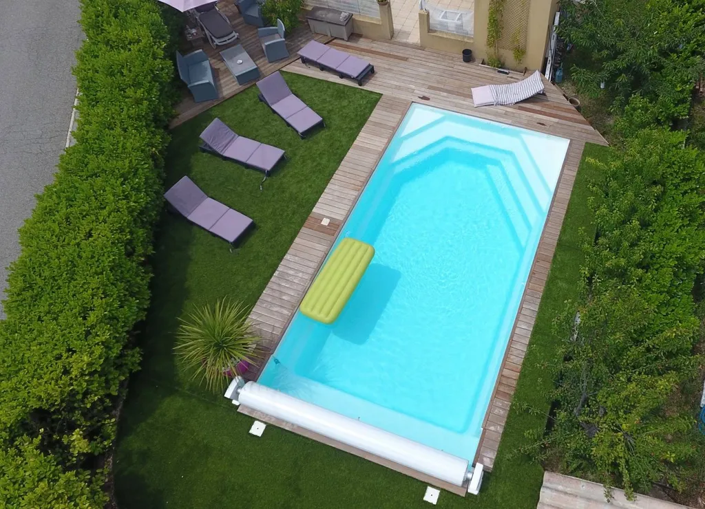 piscine avec volets dans jardin avec pelouse vue drone