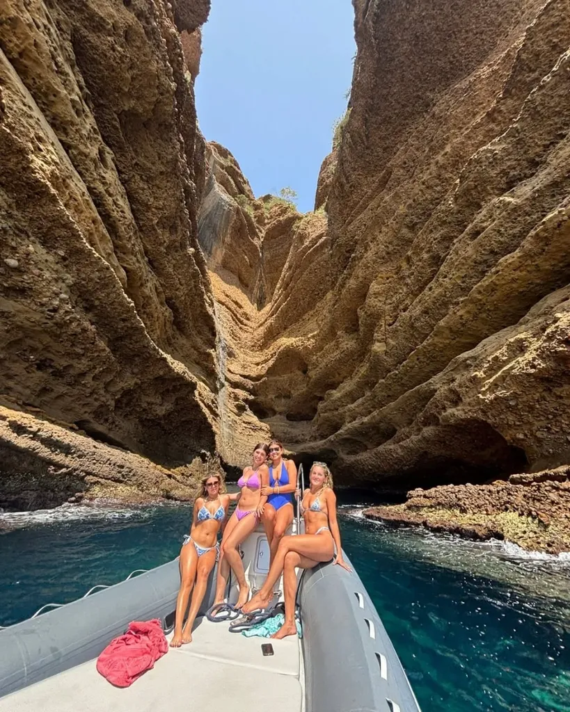 Semi-rigide de L'Eden Boat ancré dans une crique préservée des Calanques, taud de soleil déployé, groupe en baignade autour du bateau
