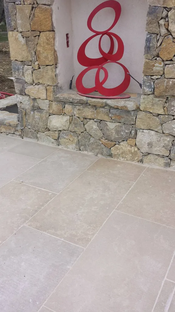 mur en pierre naturelle devant une terrasse en dallage beige
