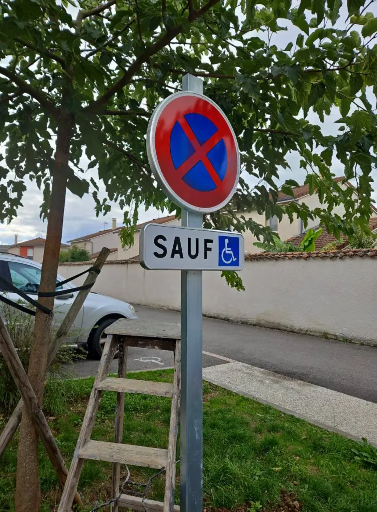Pose d'un panneau de signalisation pour réserver le stationnement aux personnes en situation de handicap sur le parking d'une pharmacie à Décines à l'est de Lyon
