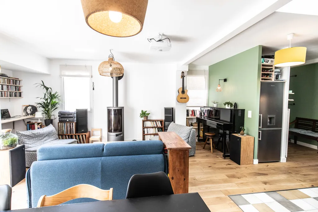 Salon, salle à manger & cuisine en enfilade  AKIKO ARCHITECTURE – Bègles – Optimisation des volumes La rénovation redessine une grande pièce de vie traversante où le bleu du canapé, le bois naturel et la cuisine noire construisent une atmosphère vivante e