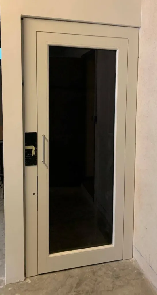 le RAL 1013 est du lus bel effet sur ette porte battante en verre transparent pour cet ascenseur de maison en intérieur à Carry le Rouet près de Marseille