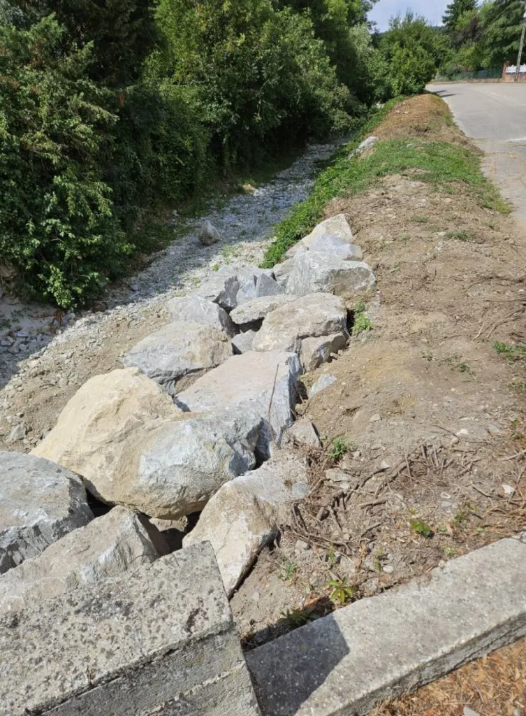 Entreprise de terrassement dans l'Ain pour Réalisation d'un enrochement brute avec grosses pierres pour soutenir le mur du fossé à l'entrée d'une maison à Saint-Genis-Pouilly