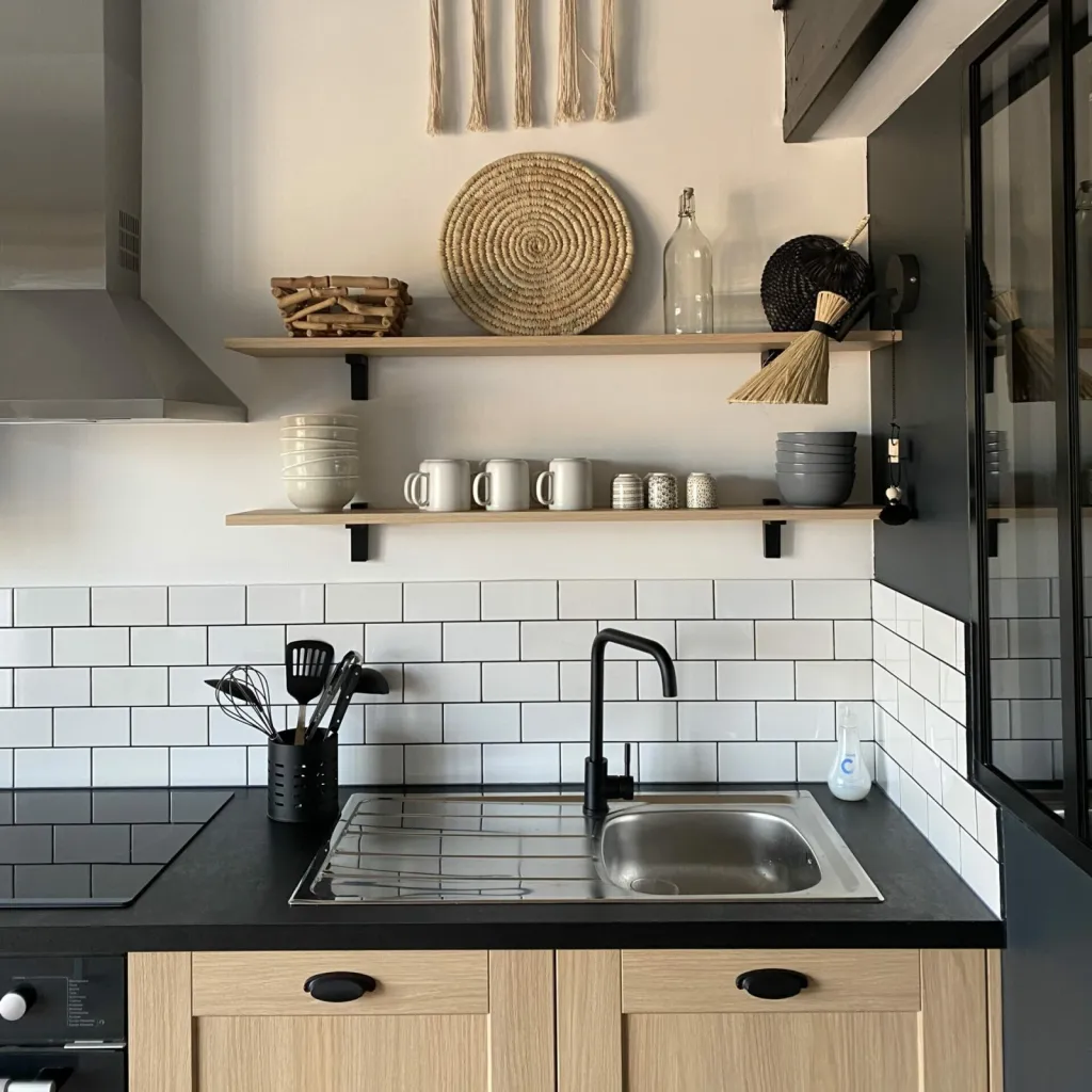 Cuisine équipée noir et bois avec mobilier en rotin et finitions élégantes, parfaitement intégrée dans le duplex, par l'Atelier D, architecte d'intérieur à Bordeaux