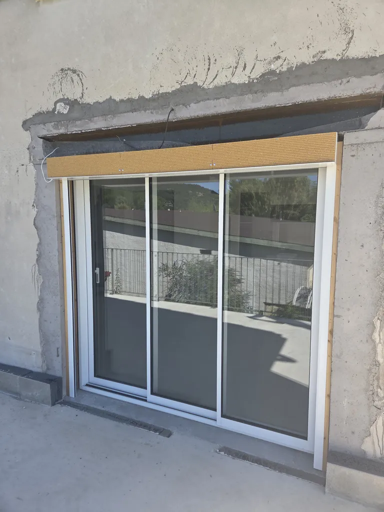 Installation à Tullins d’un coulissant aluminium trois vantaux sur trois rails et de son volet roulant posé en applique pour une isolation thermique par l’extérieur