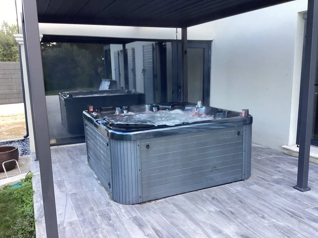 Livraison d'un spa chauffant à Piolenc, près de Bagnols-sur-Cèze, installé sur une terrasse avec pergola pour un confort optimal. - MCR Piscines et Spas - Gard