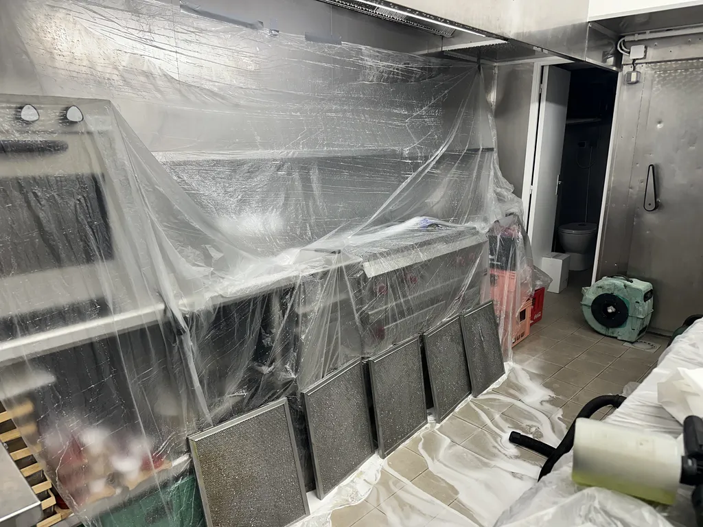 Protection complète de la zone de cuisson avant le nettoyage et le dégraissage d'une hotte professionnelle dans un restaurant à Cannes. Les filtres ont été démontés pour permettre un entretien approfondi du système d'extraction et garantir une ventilation