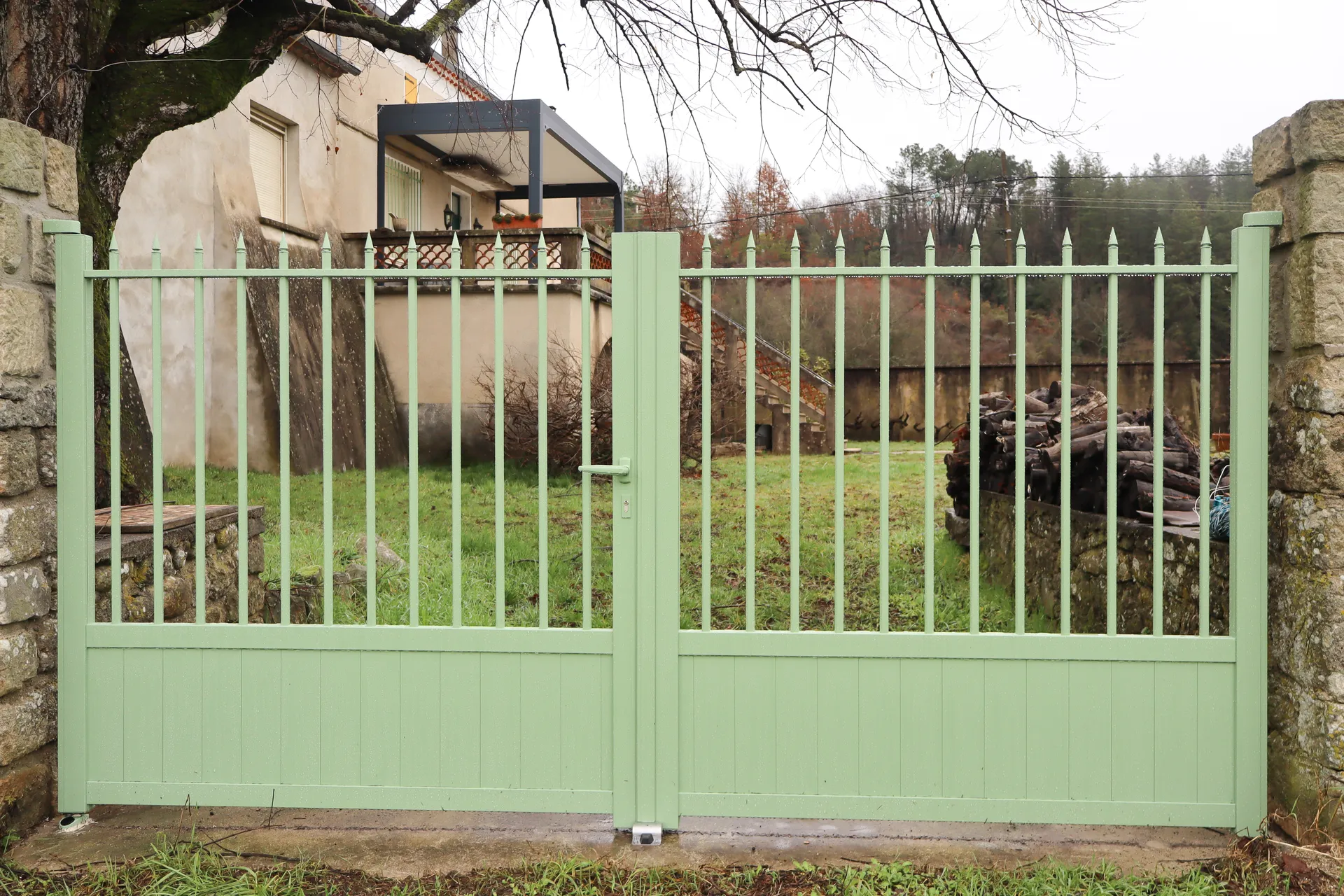 Un portail battant vert sauge qui redonne du caractère à l’entrée et souligne l’âme du jardin familial