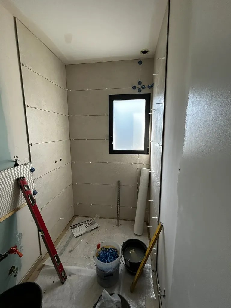 Pose de carrelage grand format au sol lors d’une rénovation de salle de bain à Lachassagne