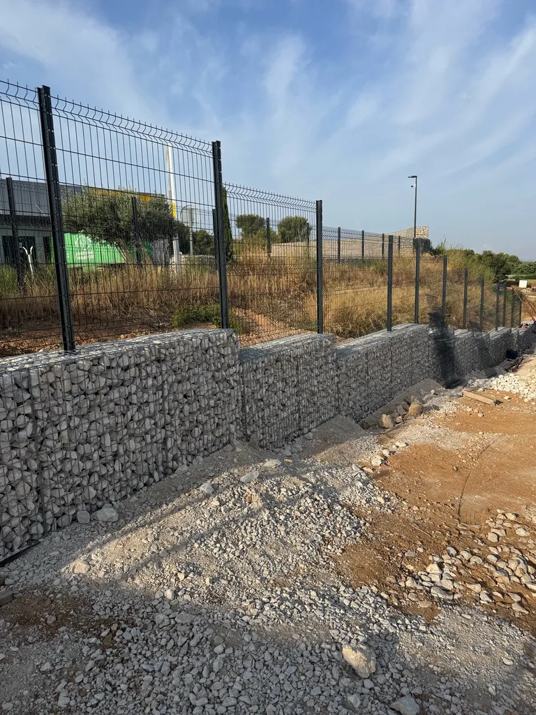 Réalisation d’un mur de clôture en gabion surélevé par une clôture en panneaux soudés pour un bâtiment industriel aux Pennes-Mirabeau