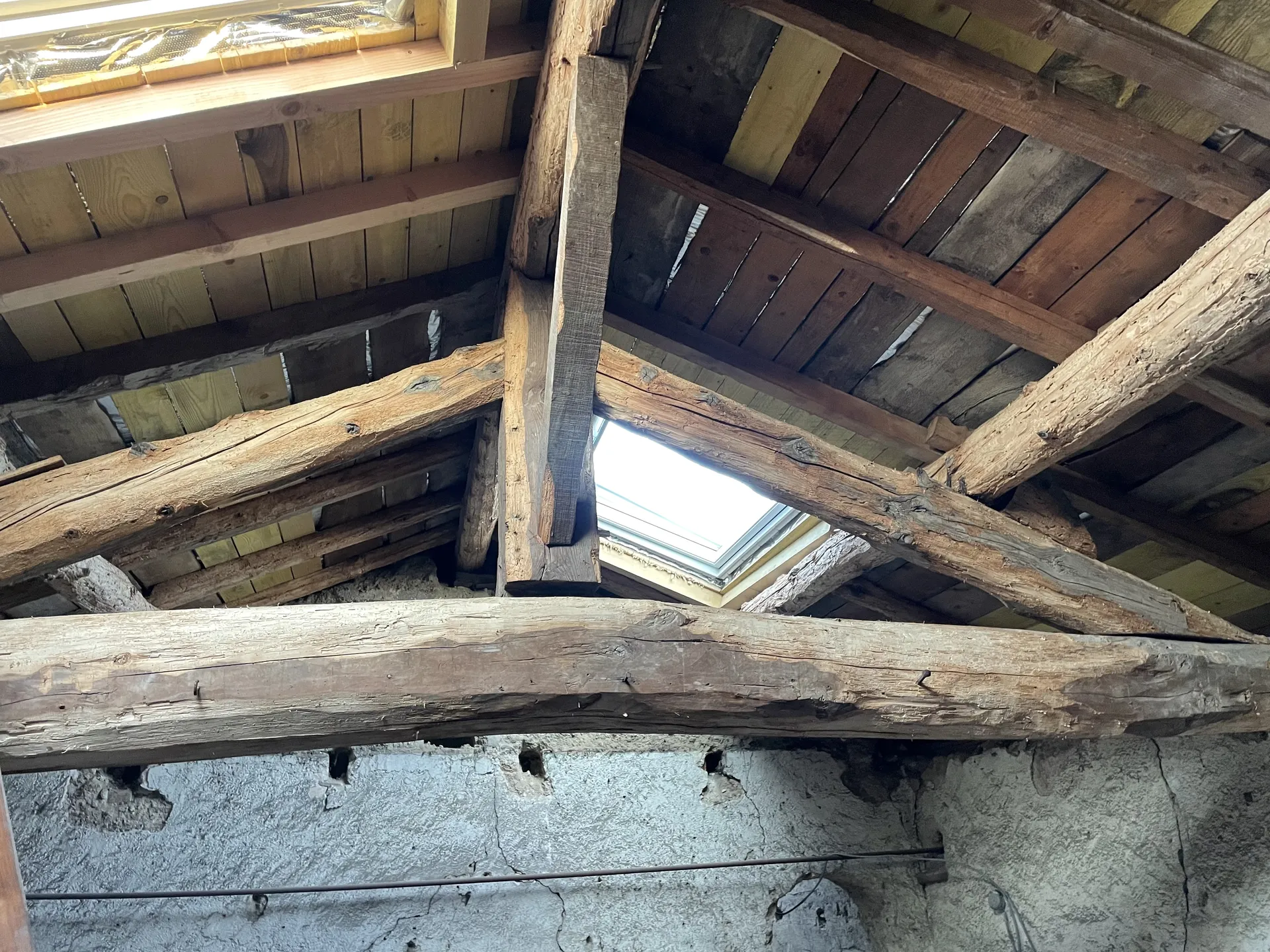 Poutres anciennes en chêne avant sablage par aérogommage dans des combles à Gleizé près de Belleville-en-Beaujolais, avant leur mise en valeur lors de l’aménagement de l’espace habitable.