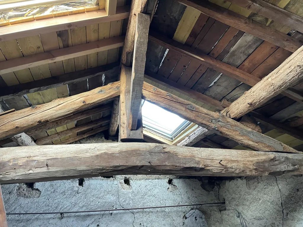 Poutres anciennes en chêne avant sablage par aérogommage dans des combles à Gleizé près de Belleville-en-Beaujolais, avant leur mise en valeur lors de l’aménagement de l’espace habitable.