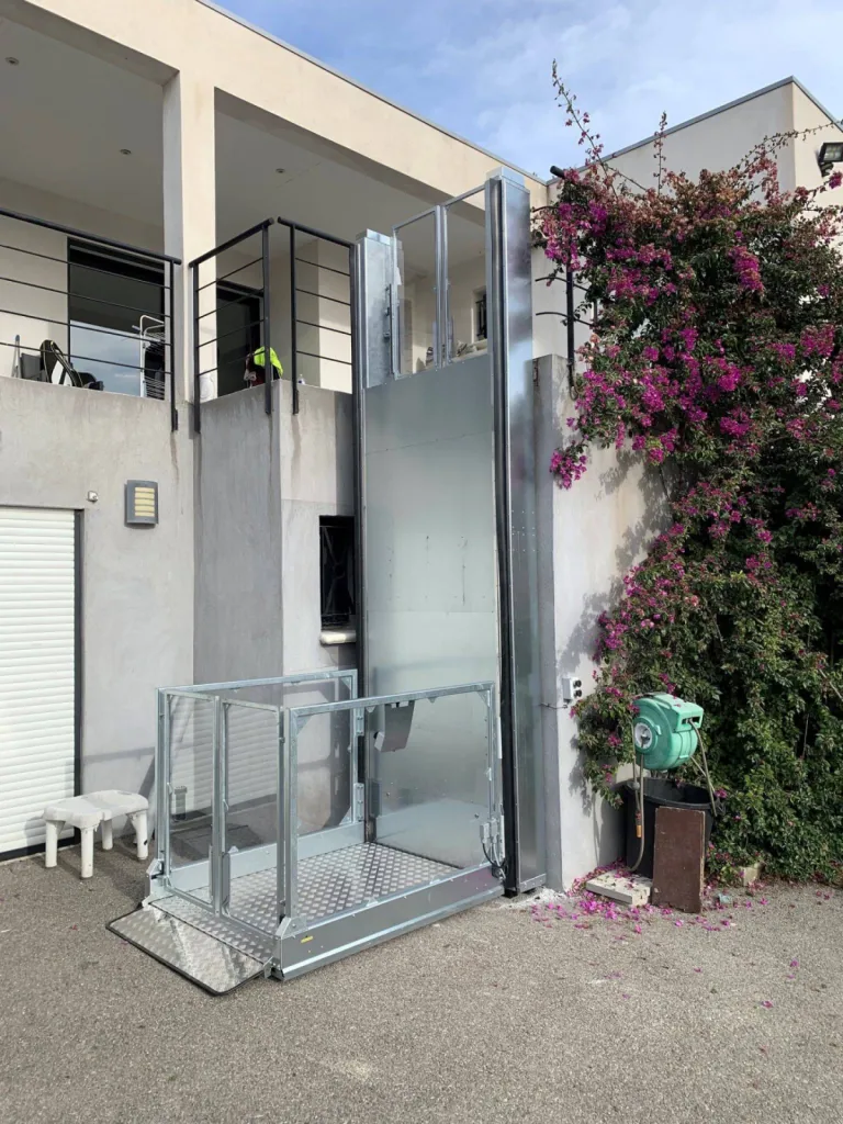 En position basse, la porte haute de cette plateforme verticale Strategos est verrouillée cela sécurise l'élévation de 3 m en extérieur à Martigues près d'Aix en Provence 