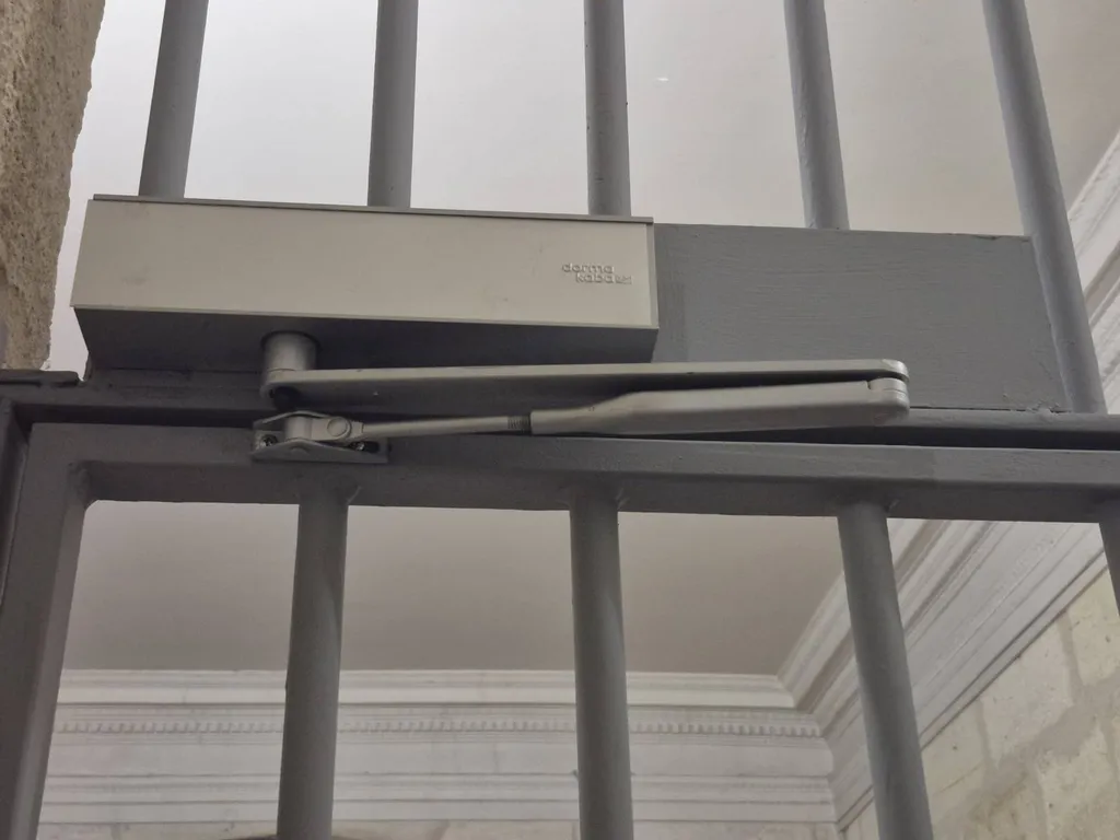 Détail du ferme-porte intégré à une grille de protection fabriquée en Gironde.