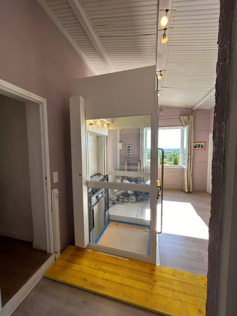 La luminosité de la pièce est préservée avec cet ascenseur de maison NAMILIFT PL 501 vitré en intérieur sur 2 nveaux dans un village entre Avignon et Aix en Provence