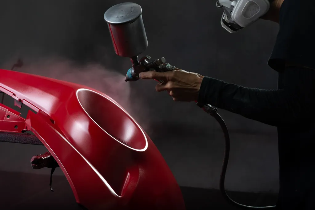 Mise en peinture d’un élément de carrosserie rouge en cabine pour une finition homogène, propre et adaptée à la teinte du véhicule.