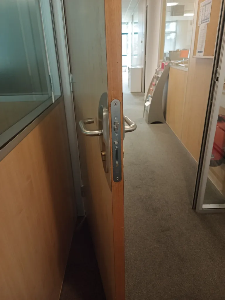 Installation d'une serrure Kel Abloy sur une porte en bois avec mortaisage de la porte pour encastrement de la serrure dans une usine de la Plaine de l'Ain à Lagnieu
