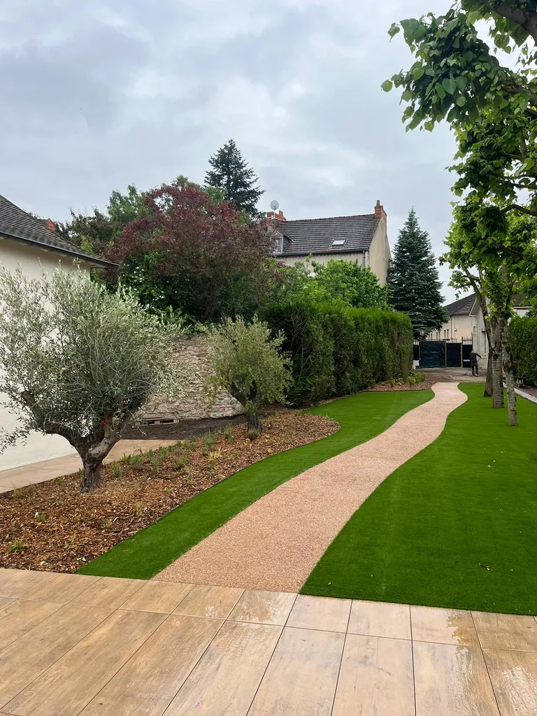 Aménagement paysager complet avec allée béton désactivé, gazon synthétique et massifs végétalisés sur mesure