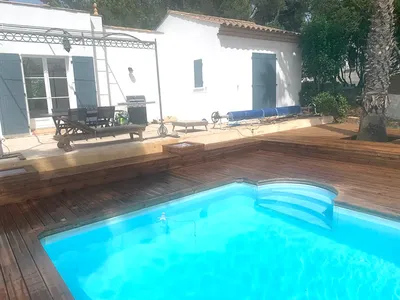 Rénovation d'un contour de piscine avec une terrasse en bois sur-mesure et jardinières intégrées à Béziers