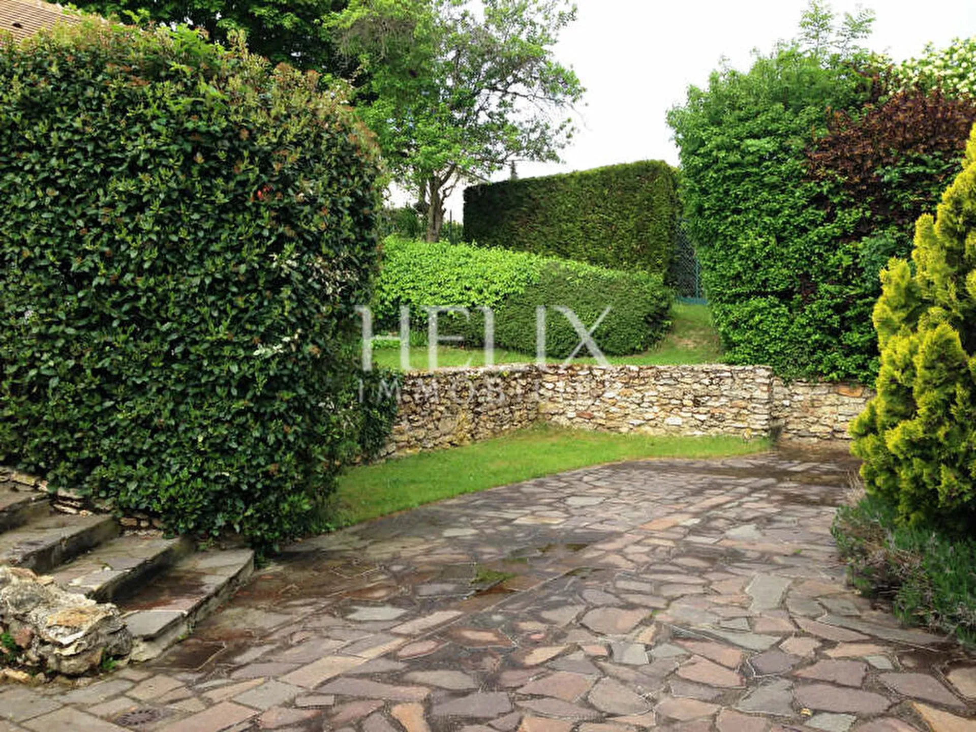 Belle maison de 170 M² à Chambourcy édifiée sur un terrain de 1006 M² joliment arborée et parfaitement entretenue, entièrement close de murets en pierre, quelques marches permettent l'accès à la maison. 