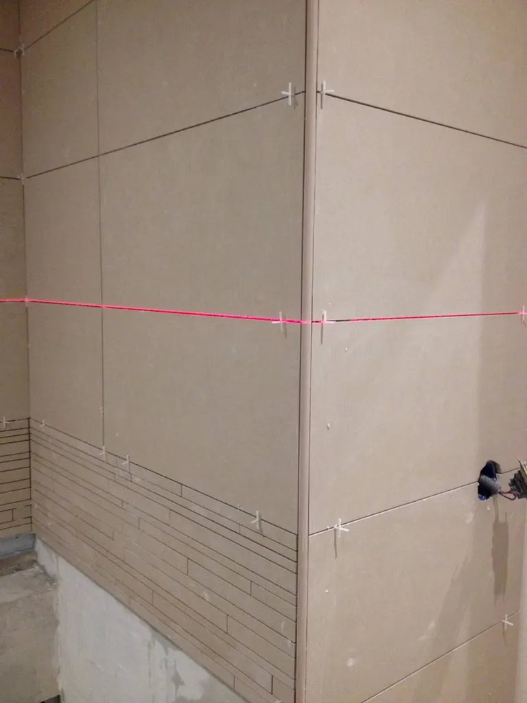 Pose de carrelage au laser en cours lors de la rénovation d’une salle de bain à Saint-Germain-au-Mont-d’Or (Rhône – 69) pour garantir un alignement parfaitement droit des carreaux