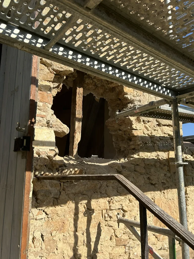 Percement chirurgical en sous-œuvre dans le mur maître en pierres pour façonner l'emplacement de la future fenêtre
