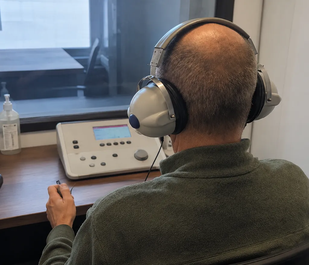 Test auditif chez un audioprothésiste à Lyon : patient réalisant une audiométrie avec casque en cabine auditive 