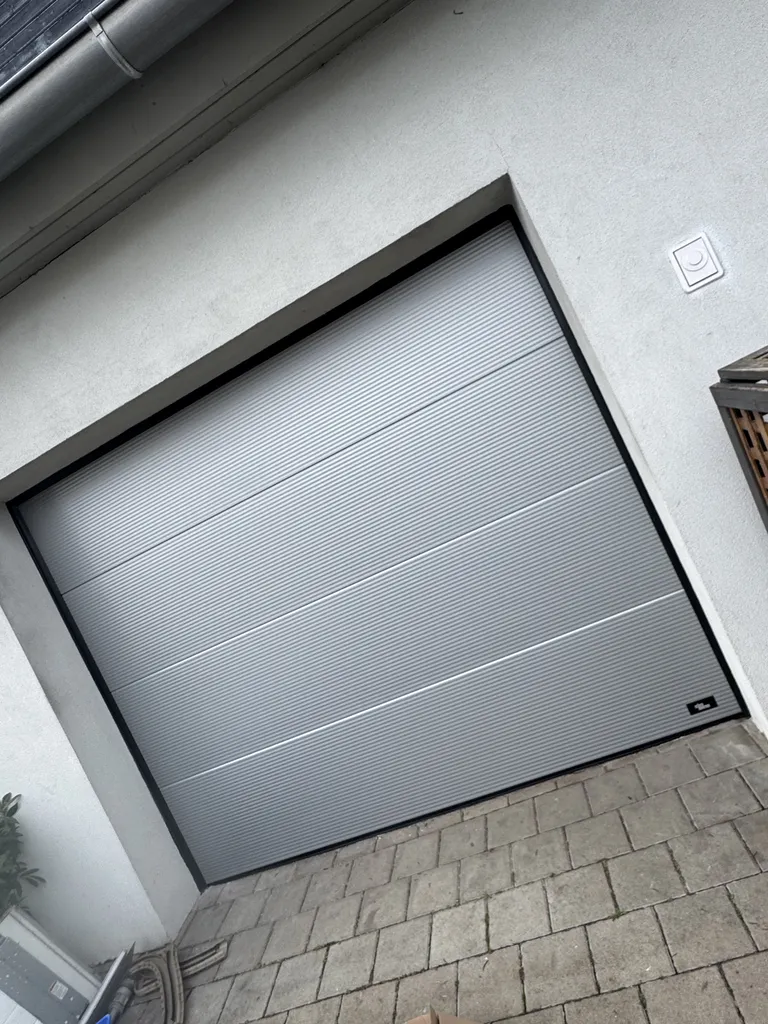 Installation de porte de garage sectionnelle motorisée Somfy avec ressorts de traction de sécurité à Colmar en Alsace