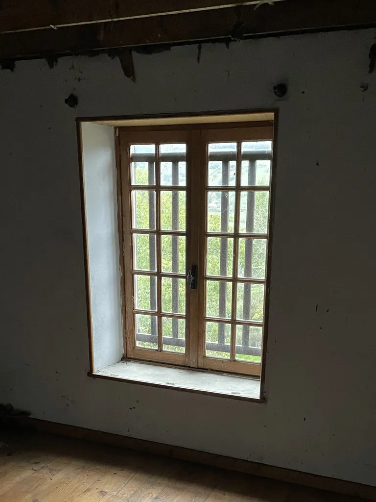 Fenêtre existante vue de l’intérieur avant agrandissement dans une maison en pierre à Beaujeu (Rhône 69) limitant la luminosité et le confort
