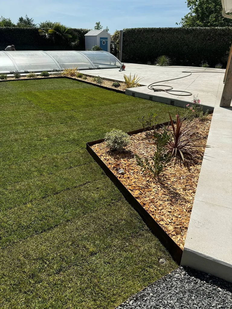 Pelouse d’un jardin changée en un espace esthétique et fonctionnel près de Bias : gazon, massifs, et paillage