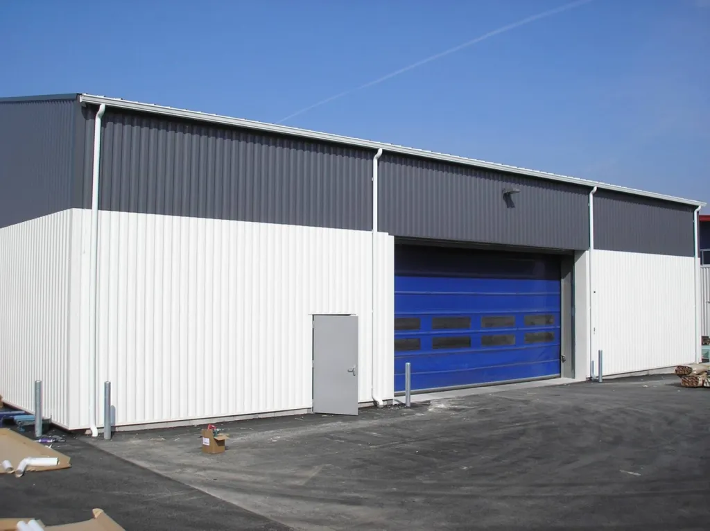 Hangar équipé de gouttières en forme de corniche avec des descentes cylindriques.