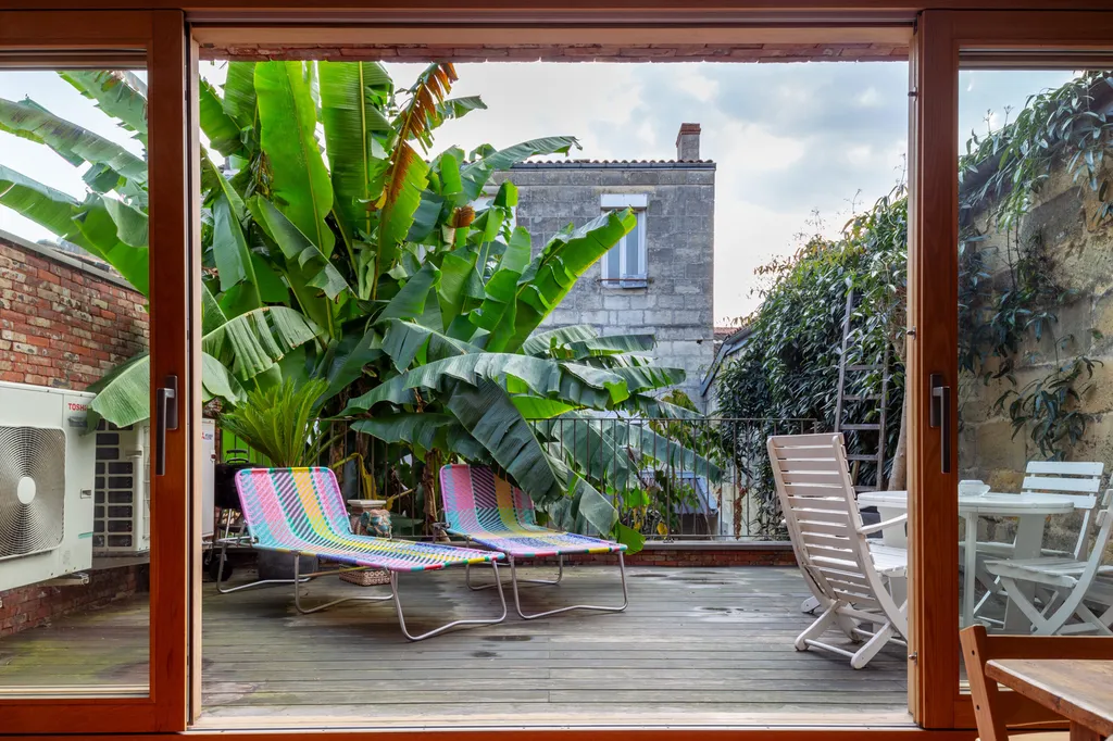 Terrasse végétalisée pensée par AKIKO ARCHITECTURE à Bordeaux Nansouty, intégrant des baies coulissantes ouvertes vers un paysage luxuriant