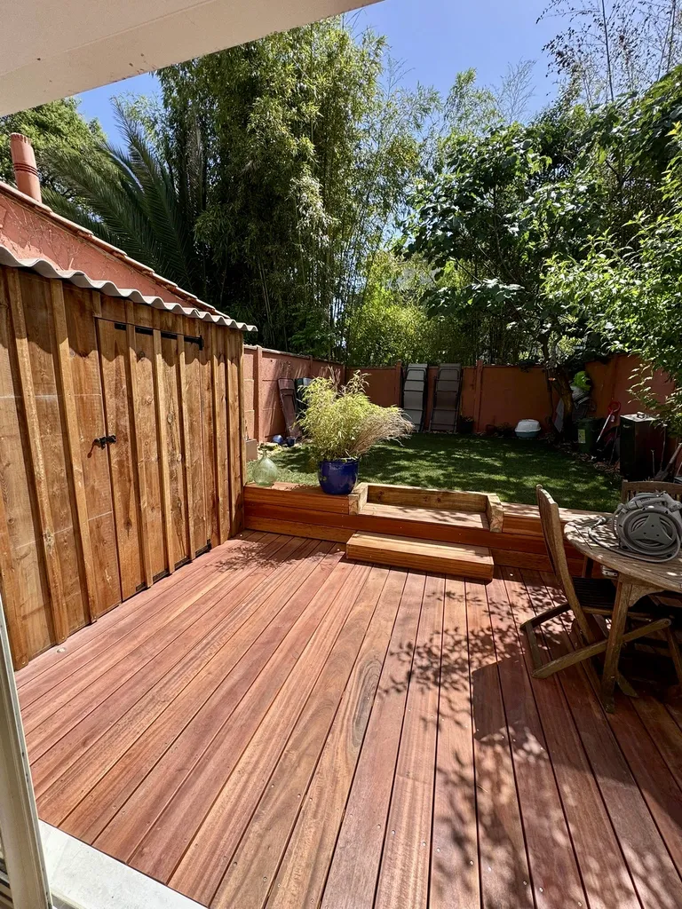 Création de jardin avec terrasse en Muiracatiara, abri de jardin en volige pin marron et gazon plaque avec arrosage automatique à Bordeaux
