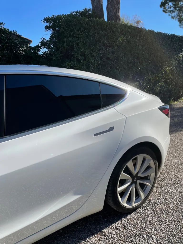 Pose d'un film solaire sur le vitrage de cette Tesla Model 3 à Antibes